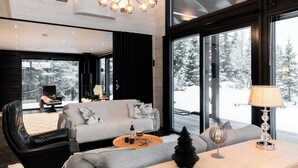 A modern living room with a grey sofa, black leather chair, and a wooden coffee table. - High-Quality 4BR Villa in Ruka - Private Hot Tub & Sauna (Kuusamo)