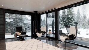 A modern interior with large windows, a fireplace, and three chairs. - High-Quality 4BR Villa in Ruka - Private Hot Tub & Sauna (Kuusamo)