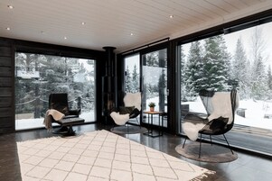A modern interior with large windows, a fireplace, and three chairs.