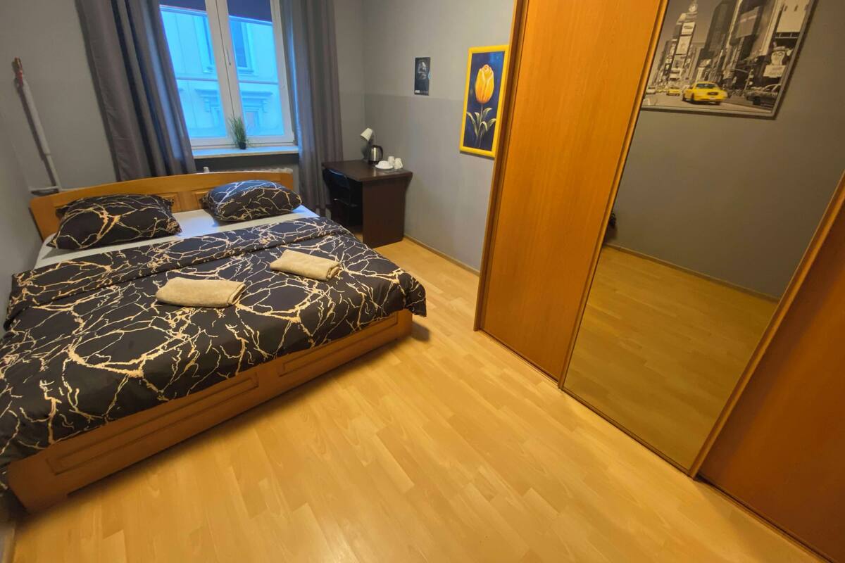 A bedroom with a bed, a desk, a window, and a door.