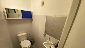 A small, compact bathroom with a toilet, sink, and mirror. - Fantastic Inn Warsaw - CH16 (Warsaw)
