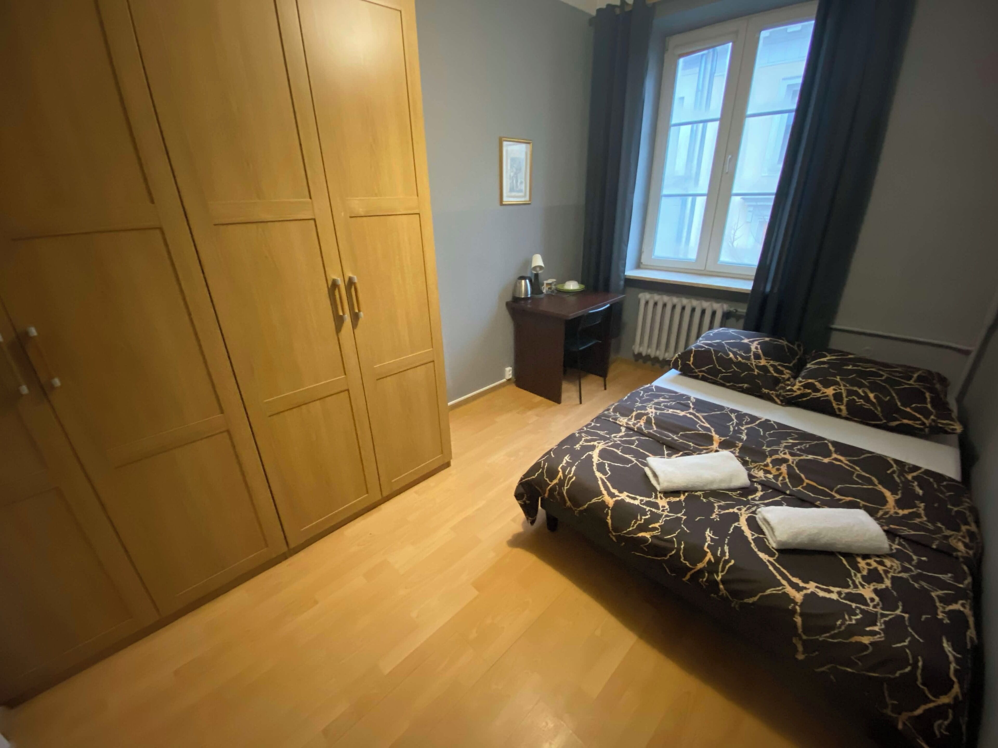 A bedroom with a bed, a desk, a chair, and a wardrobe.
