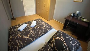 A bedroom with a bed, a wardrobe, a desk with a kettle, and a framed picture on the wall. - Fantastic Inn Warsaw - CH16 (Warsaw)