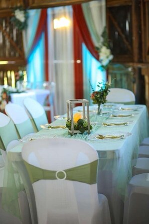 A banquet hall with rows of tables set for a formal event, chairs with green sashes, and a decorative centerpiece. - Sunshine Cabanas At Ocean View (Dangriga)