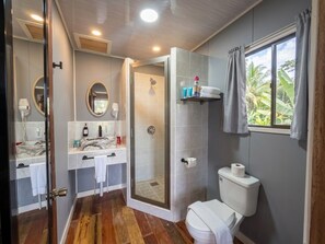 A bathroom with a shower, toilet, and two sinks with mirrors. - Sunshine Cabanas At Ocean View (Dangriga)