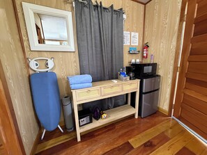 Una kitchenette compacta con microondas, cafetera y un refrigerador pequeño.