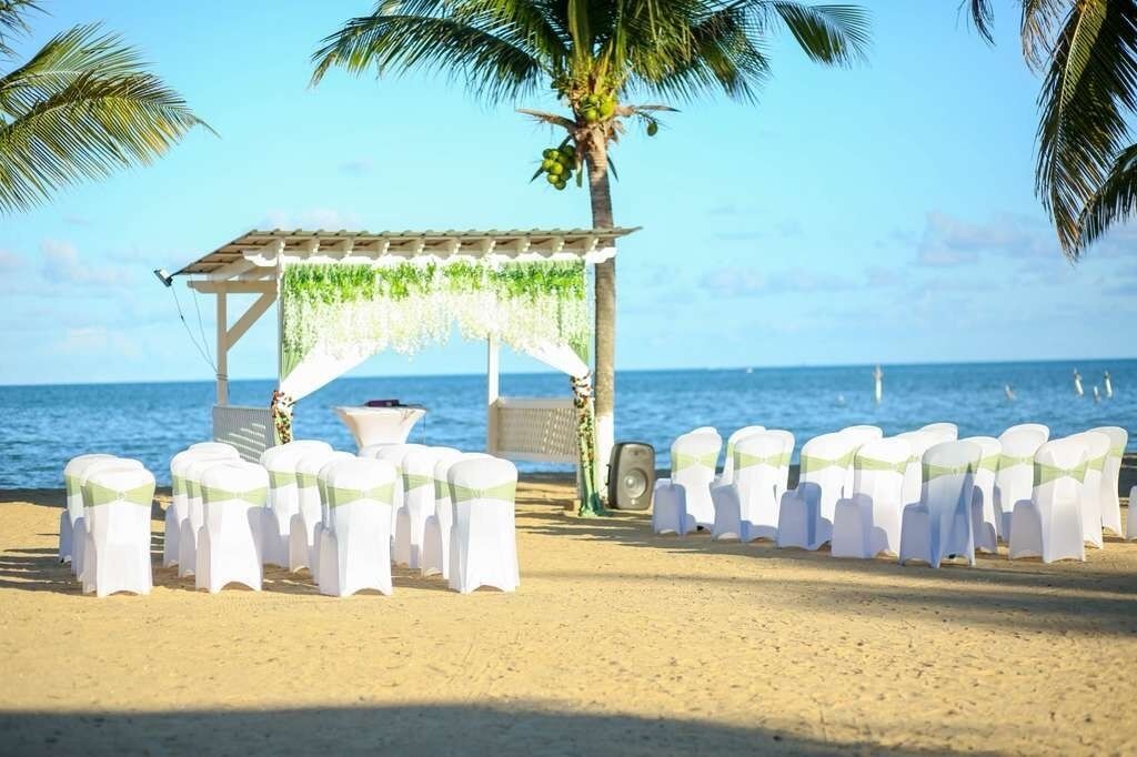 Preparación para una boda en la playa, con un toldo, sillas y un altavoz.