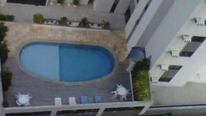 Un edificio con un patio central que cuenta con una piscina, varios balcones y zonas de estar al aire libre.