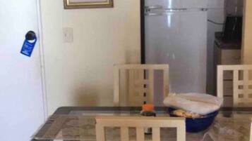 Uma área de refeições com uma mesa de vidro, cadeiras de madeira e uma tigela azul sobre a mesa.