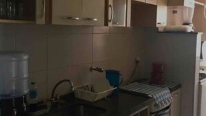 Una cocina con armarios, un lavamanos, dispensador de agua y cafetera.