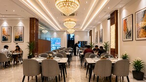 A restaurant with multiple dining tables, chairs, chandeliers, and framed artwork on the walls. - Hotel Grand Shalimar by JMD Group (New Delhi)