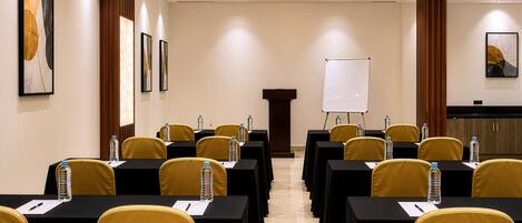 A conference room with tables, chairs, a podium, and a whiteboard.