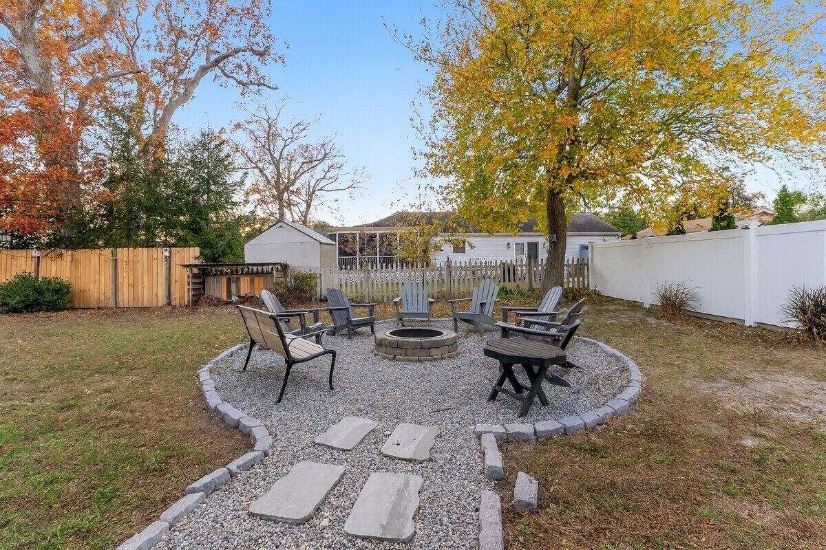 A backyard with a fire pit, seating area, and a wooden fence.