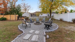 Un patio trasero con una chimenea, una zona de estar y una valla de madera.