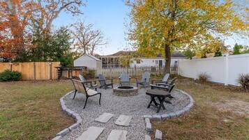 A backyard with a fire pit, seating area, and a wooden fence.