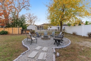 Ein Garten mit Feuerstelle, Sitzgelegenheit und Holzzaun.