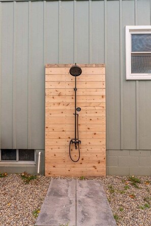 A wooden door with a showerhead and hose, set against a grey wall with a window. - Pet Friendly 4 Bedroom House in North Cape May (Lower Township)