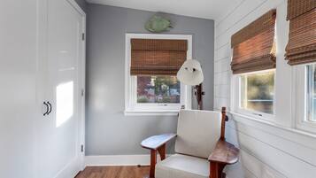 A room with a wooden chair, a white lamp, and a window with blinds.