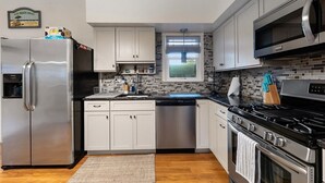 Una cocina moderna con electrodomésticos de acero inoxidable, armarios blancos y un salpicadero de azulejos.