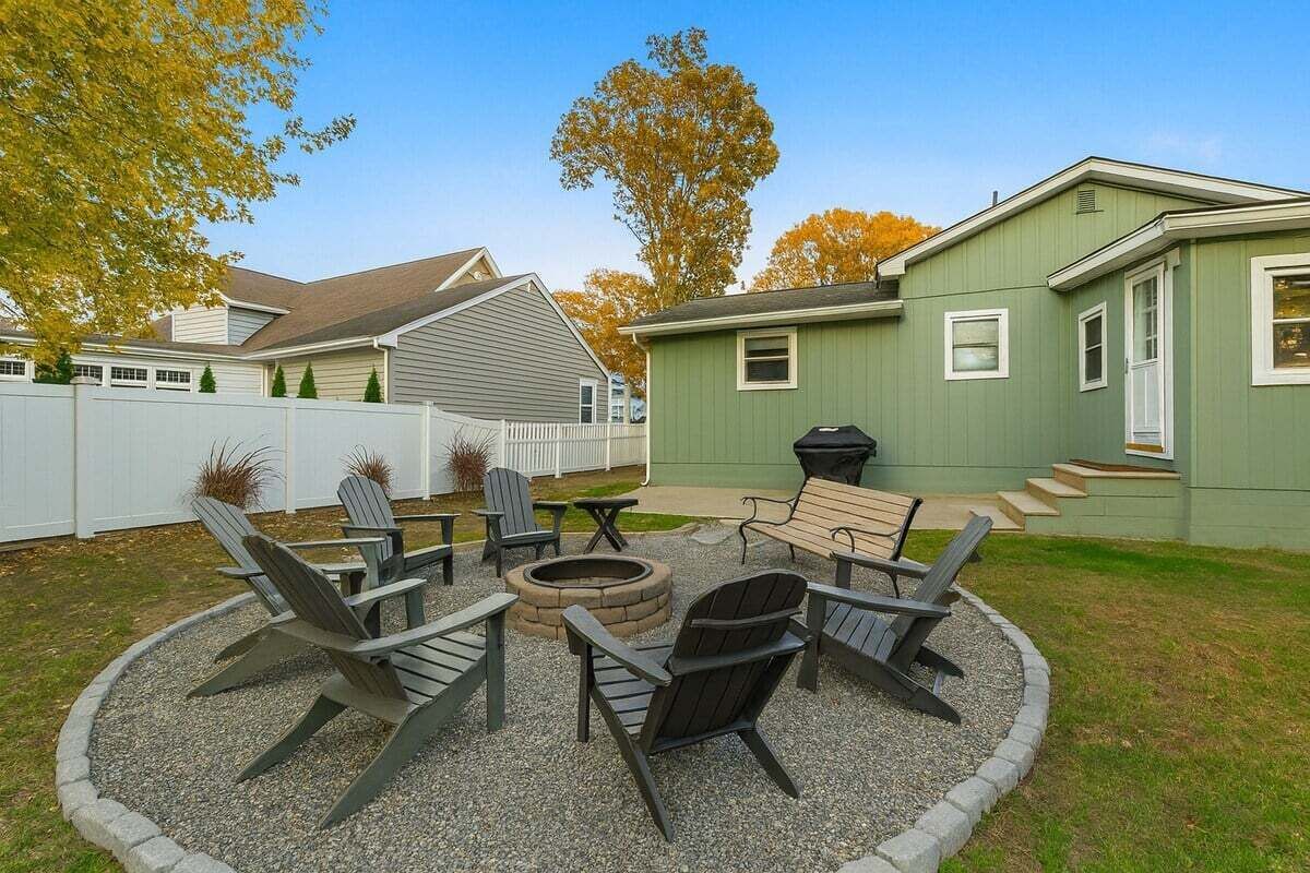 A backyard with a fire pit, seating, and a grill area.