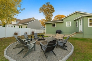 A backyard with a fire pit, seating, and a grill area.