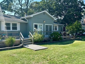 A residential property with a front porch, a wooden staircase, and a small garden area. - Pet Friendly 4 Bedroom House in North Cape May (Lower Township)