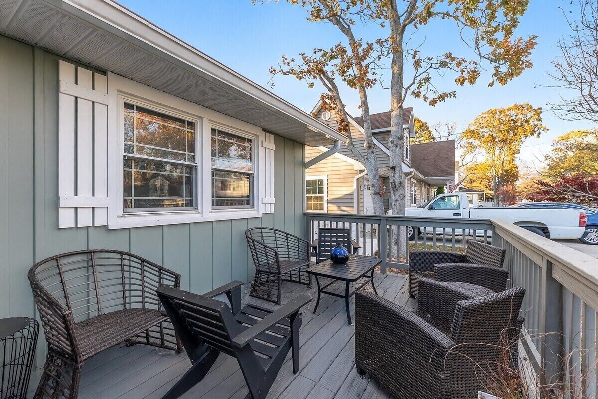 A covered porch with outdoor furniture, a railing, and a view of the street.