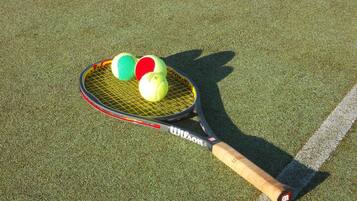 A tennis racket with three tennis balls on a green surface.