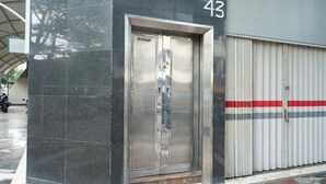 A building entrance with a metallic elevator and a garage door. - ARA Stay By ARBA (Bandung)