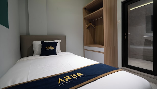 A hotel room with a bed, a wardrobe, and a sliding glass door. - ARA Stay By ARBA (Bandung)