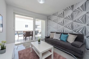Ein modernes Wohnzimmer mit einem grauen Sofa, einem weißen Couchtisch und einer Wand mit Muster.