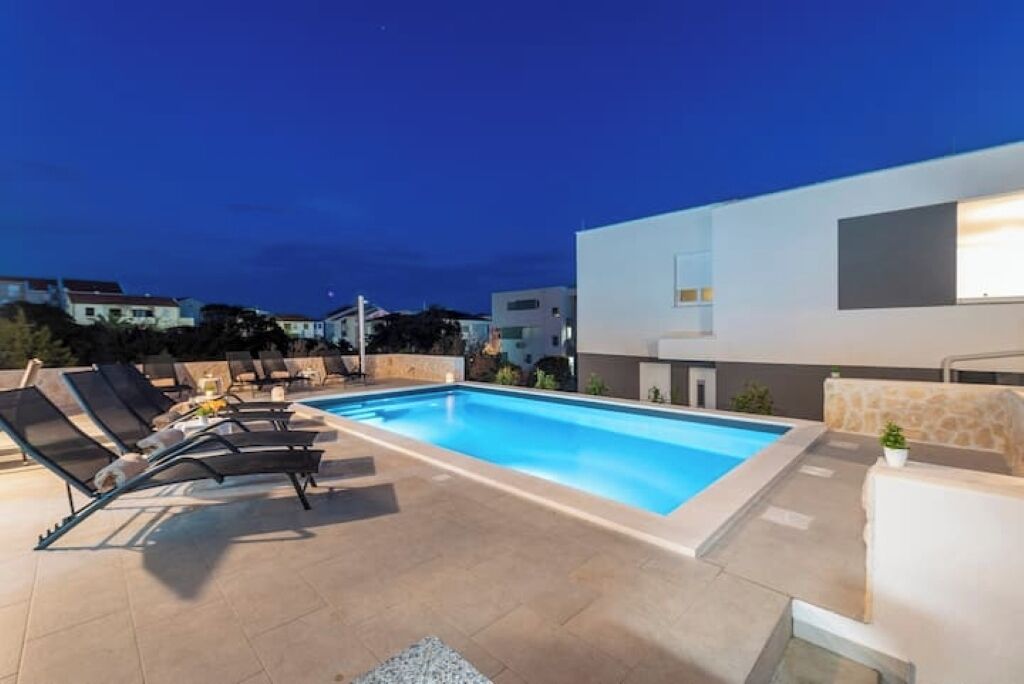Ein moderner Poolbereich mit Liegestühlen und einer Steinwand.