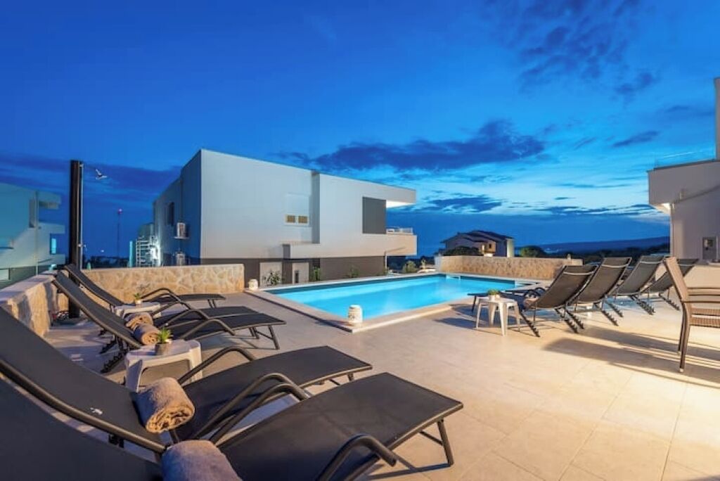 A modern poolside area with lounge chairs and a swimming pool, surrounded by contemporary architecture.