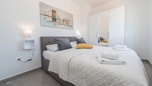 Quarto moderno com cama, abajures, um quadro e um guarda-roupa.