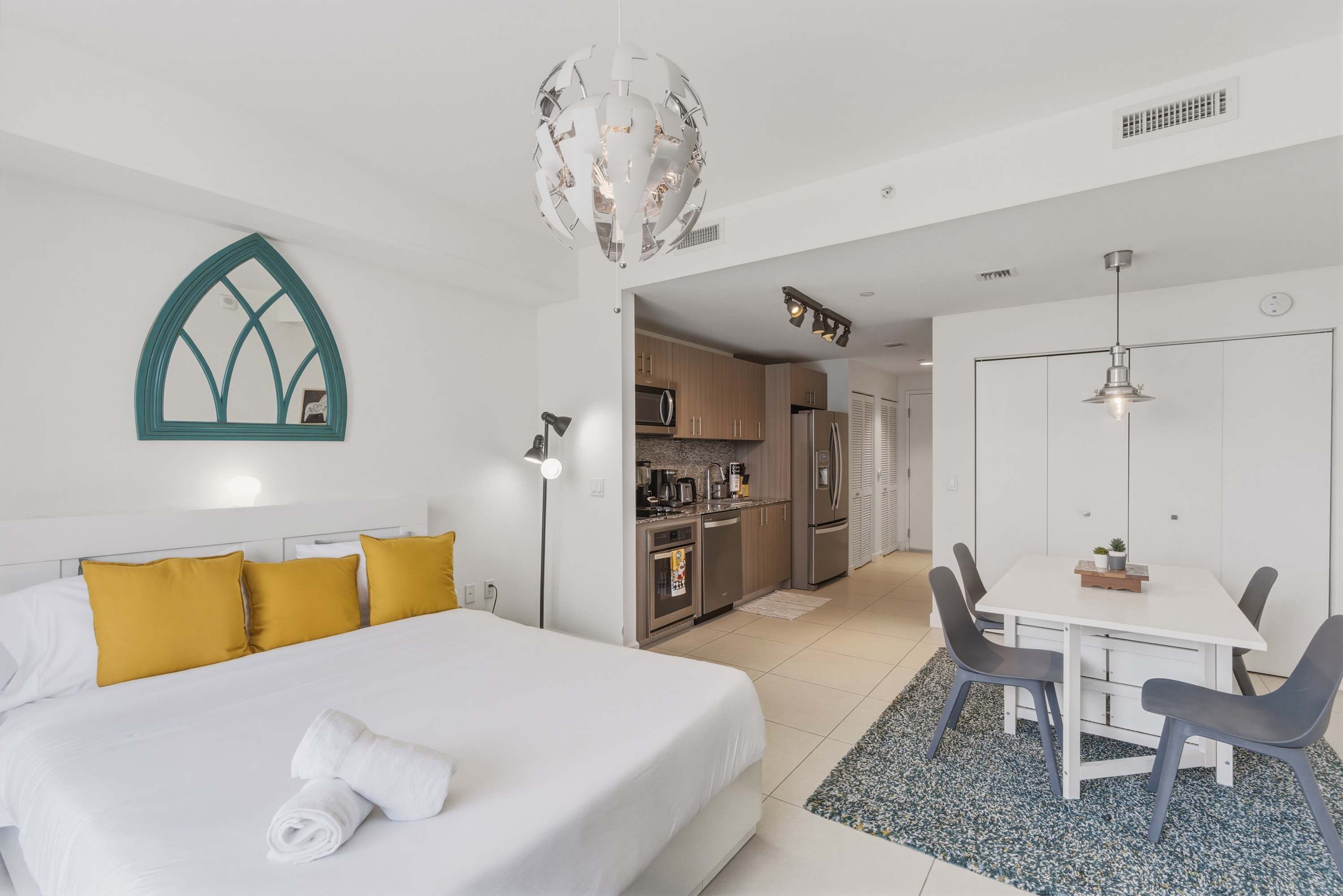 Habitación de hotel con cama, escritorio y kitchenette.