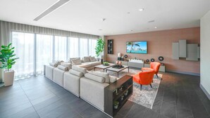 A modern living room with a sectional sofa, a coffee table, and a TV mounted on the wall. - Studio in the Heart of Downtown Doral | Pool (Doral)