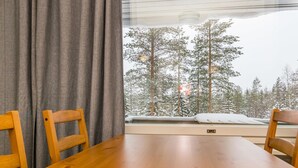 Ein Holztisch mit zwei Stühlen, ein Fenster mit Blick auf schneebedeckte Bäume.