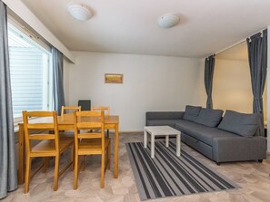 Un salon avec un canapé, une table à manger et des chaises, une petite table et un tableau au mur.