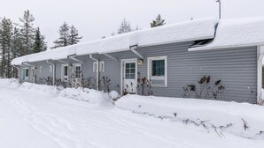 Eine Reihe einstöckiger Holzhütten mit grauer Schale und weißem Verkleidung, bedeckt mit Schnee.