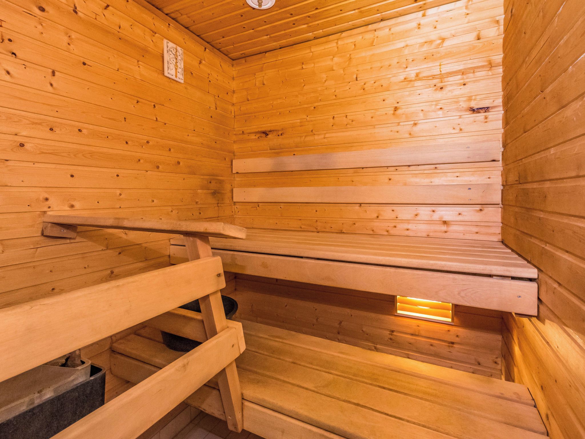 Una sala de sauna con bancos de madera y un banco con perchero para toallas.