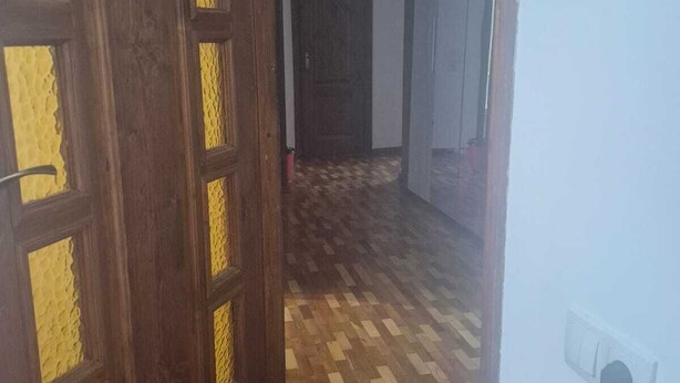 A hallway with wooden flooring and a door with yellow patterned glass panels. - apartament confort in chisinau (Chișinău)