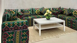 A modern living room with a sectional sofa, a coffee table, and a wall clock. - Appartement propre à Rabat – Location journalière (Rabat)