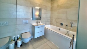 Een moderne badkamer met een badkuip, toilet en wastafel.