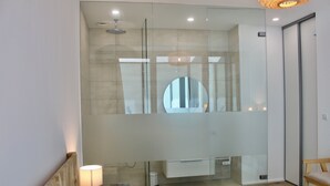 Een moderne badkamer met een douchecabine van glas, een grote spiegel en een ingebouwde bank.