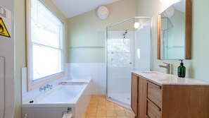 Ein modernes Badezimmer mit einer Badewanne, einer Duschkabine und einem Waschtisch mit Spiegel.