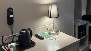 A hotel room with a desk, a telephone, a coffee maker, a remote control, a lamp, and a television. - PARIS ROOMS & DREAMS HOTEL (Paris)