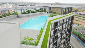 A rooftop pool with a view of the cityscape, surrounded by greenery and modern architecture. - A Plush Studio at Loxwood House (Accra)