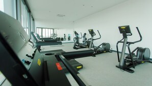Une salle de sport équipée de divers appareils d’exercice, notamment des tapis de course et des vélos d’appartement.
