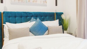 Un lit bien fait, avec une tête de lit bleue, du linge de lit blanc et des coussins décoratifs.