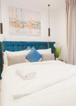 A neatly made bed with a blue headboard, white bedding, and decorative pillows. - A Plush Studio at Loxwood House (Accra)